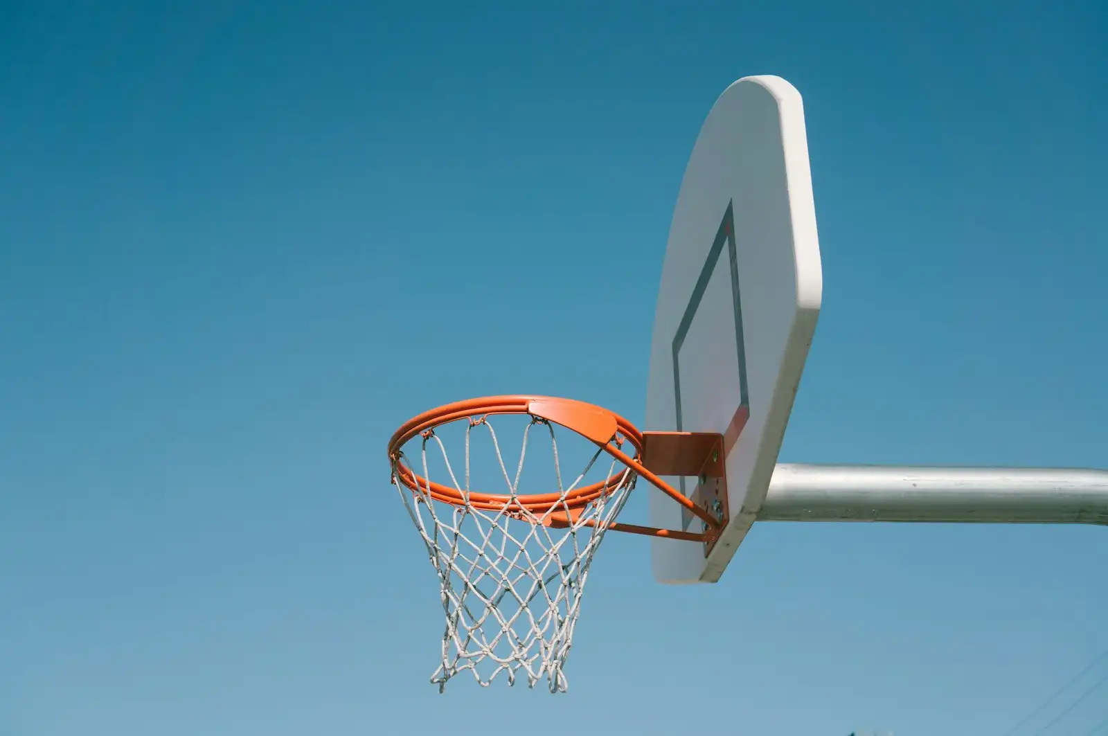 Outdoor basketball hoop against a clear blue sky